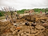 father-removes-the-grass-and-plastic-from-the-roof-structure-of-his-collapsed-home